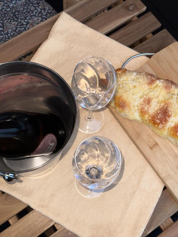 Wine glasses and bread on a wooden table outdoors.