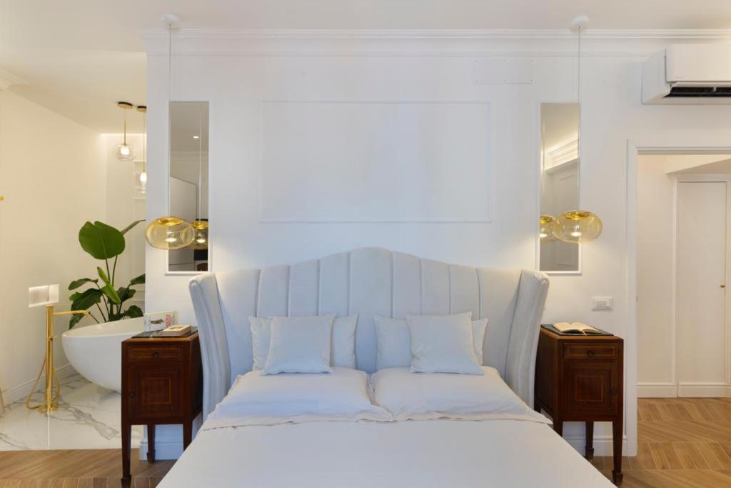 a bedroom with a white bed and a bath tub at Île Déluxe Apartment in Sorrento