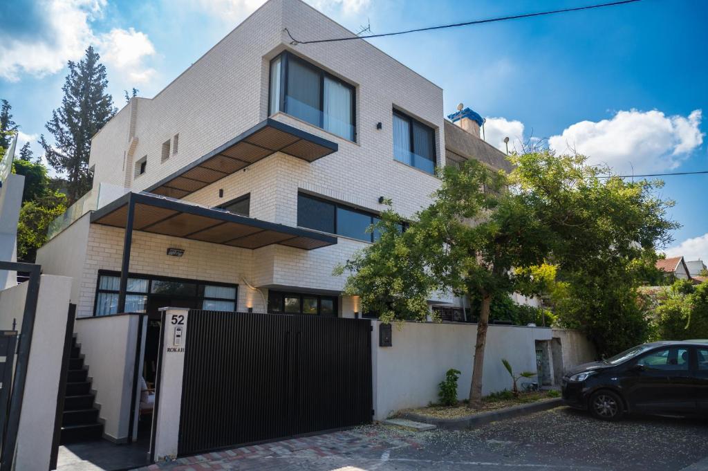 una casa blanca con una valla negra delante de ella en Rokah Luxury Hotel at Ramat HaHayal en Tel Aviv