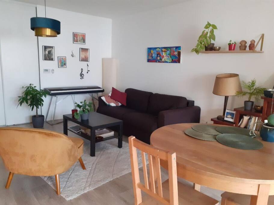 ein Wohnzimmer mit einem Tisch und einem Sofa in der Unterkunft Appartement à 15 min de l'océan in Bayonne