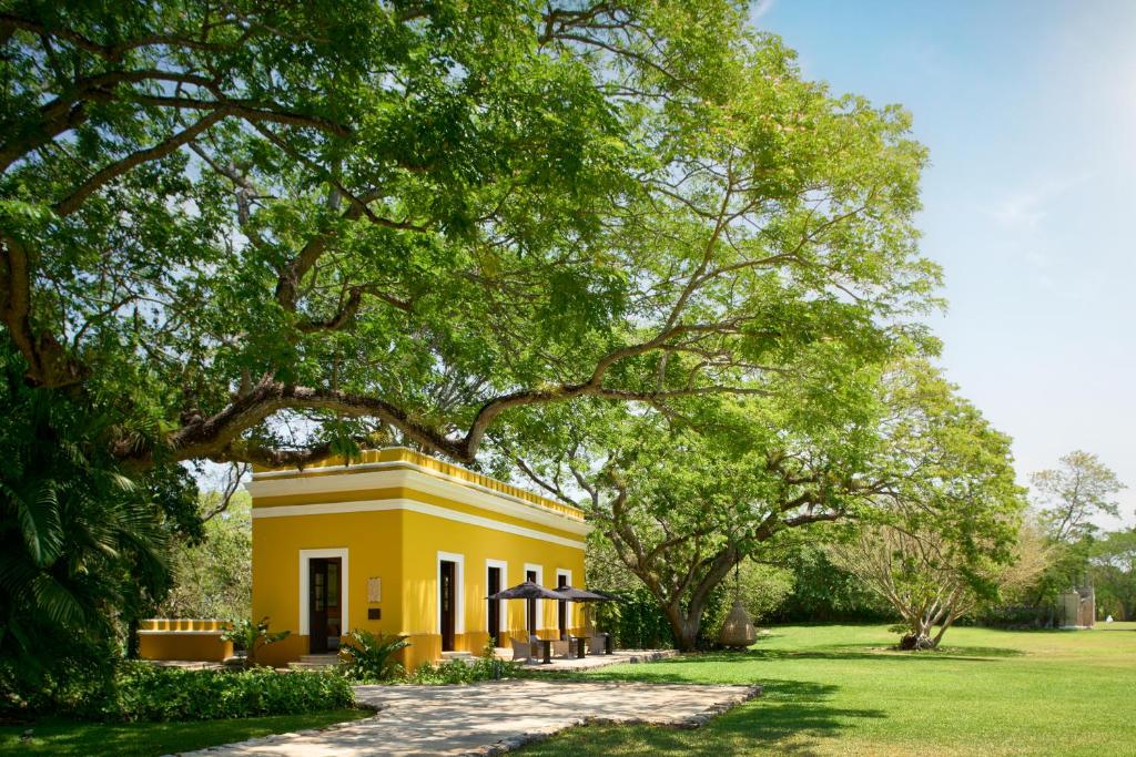 een geel huis in een veld met bomen bij Chablé Yucatan in Chocholá