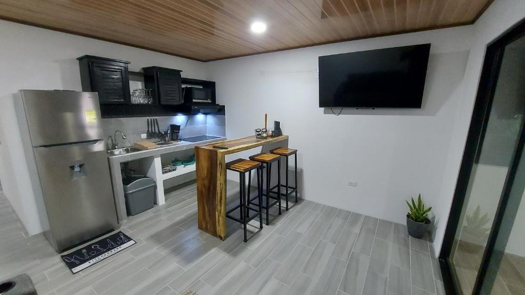 een keuken met een koelkast en een tv aan de muur bij Casas Dñ Juanita in Jacó