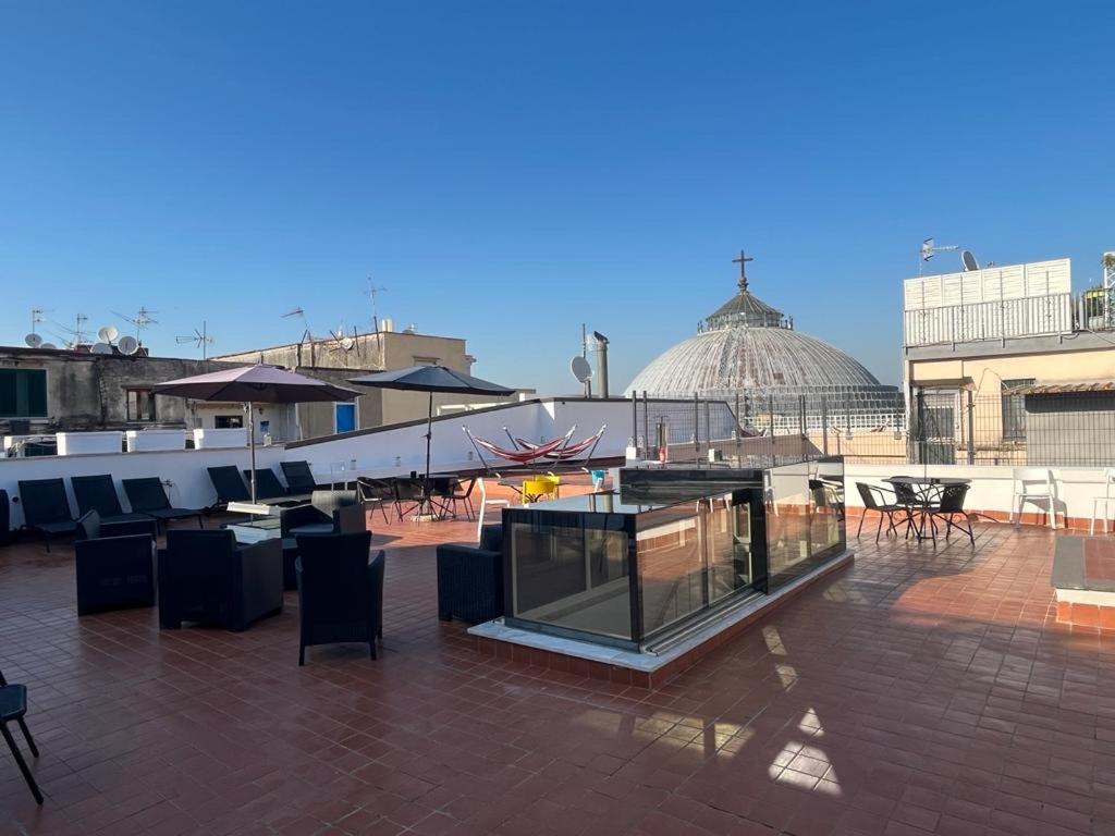 a rooftop patio with tables and chairs and a building at Lucullo's Rooftop in Naples
