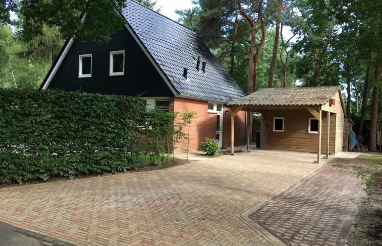 een huis met een zwart dak en een stenen oprit bij Luxe boshuis in hartje Drenthe in Spier