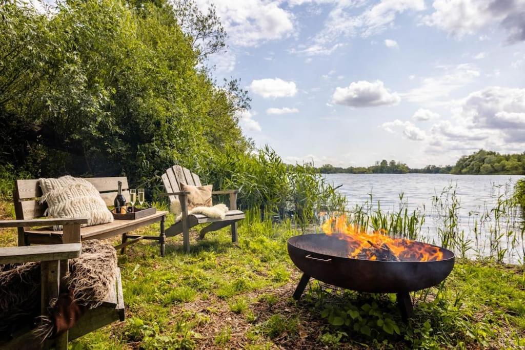 a fire pit next to a bench and a lake at The Lakeside Viewing Gallery in Shiplake