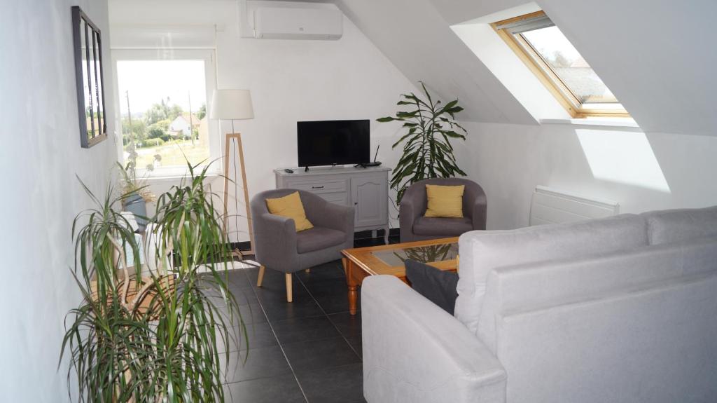 Una sala de estar con un sofá y sillas y un televisor. en Sur la route des Monts, en Bailleul