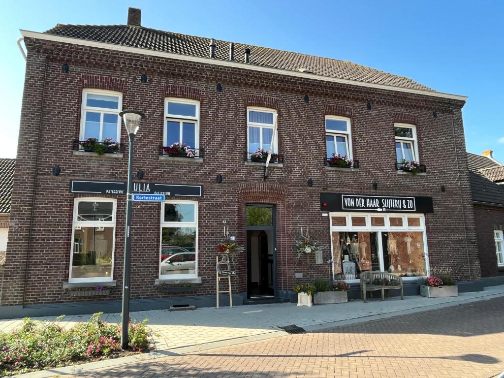 un grand bâtiment en briques rouges avec des fenêtres donnant sur une rue dans l'établissement B&B de Blauwververij, à Blitterswijck