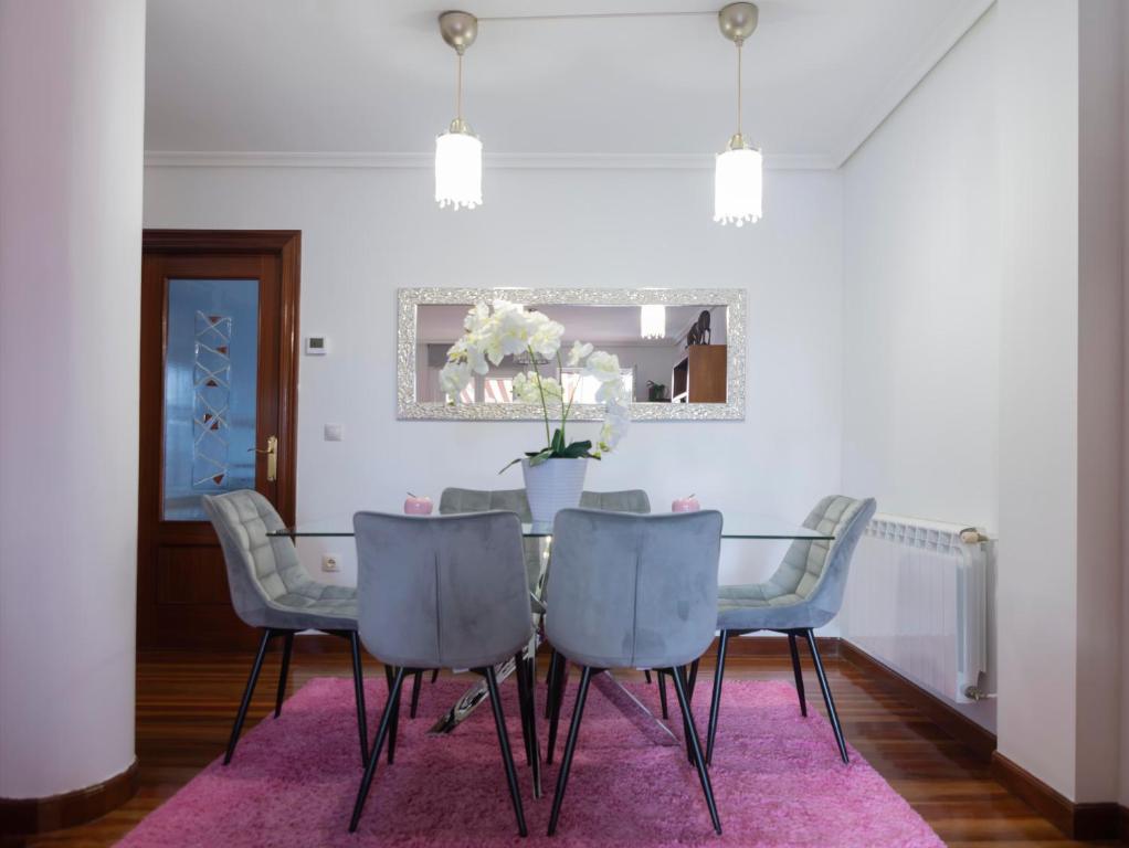 a dining room with a table and chairs on a pink rug at APARTAMENTO COSTA CANTABRIA in Cuchia