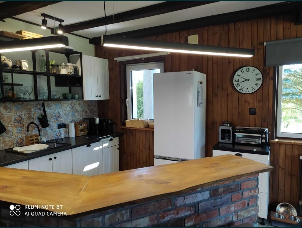 eine Küche mit einem weißen Kühlschrank und einer Uhr an der Wand in der Unterkunft Domek na Górce - Mazury, Mrągowo in Borowe