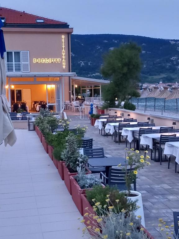 a patio at a restaurant with tables and chairs at Hotel Dobrovit in Baška