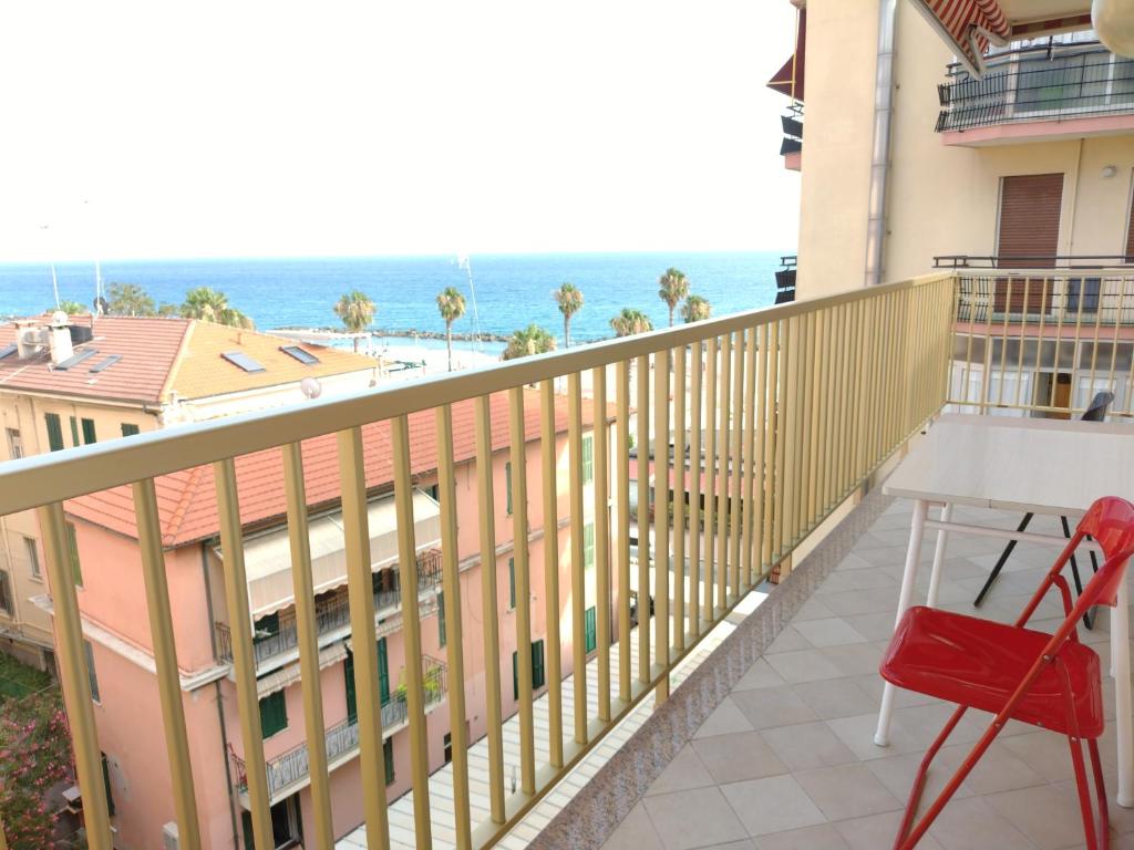 Un balcón con una silla roja y vistas al océano. en CASA FRONTE MARE, en Ventimiglia