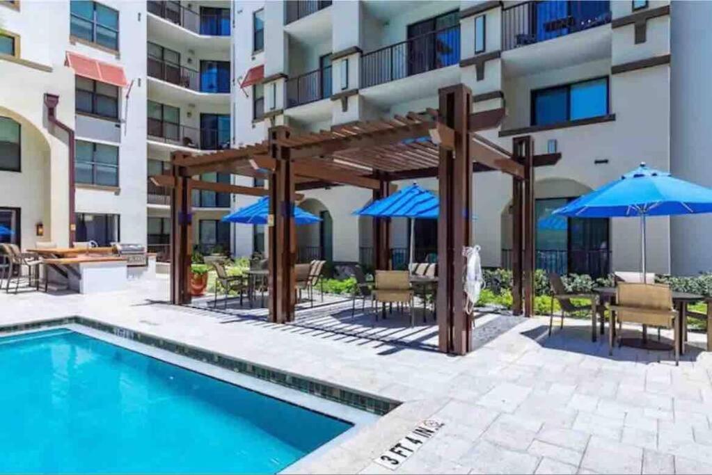 a pool with tables and chairs and umbrellas next to a building at Blooming Journey in Tampa Bay! in Tampa