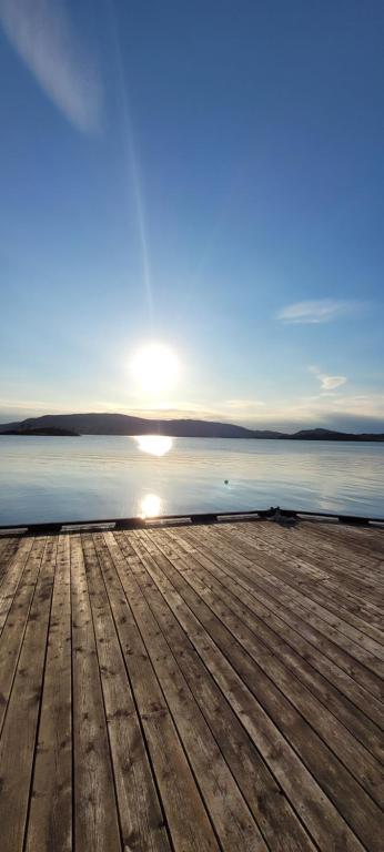 a wooden pier with the sun setting over the water at Fjord apartment 