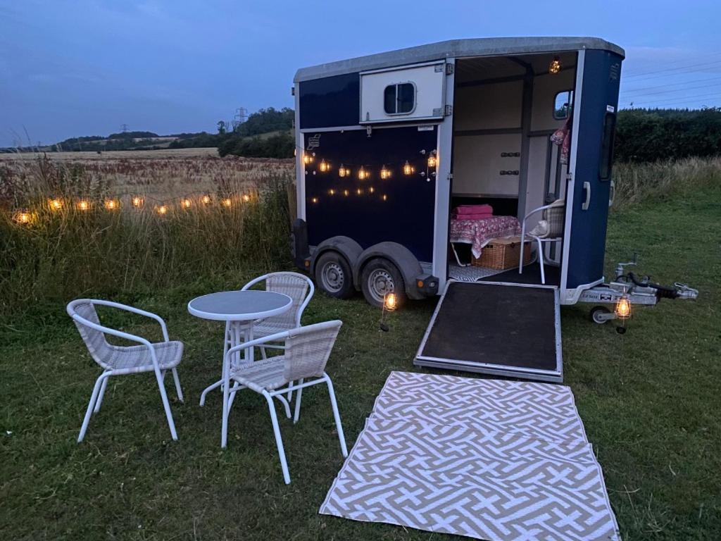 una cabaña con mesa y sillas en un campo en Glamping with a twist, en Charlton