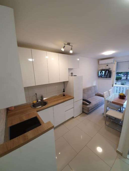 a kitchen with white cabinets and a living room at Apartman Mila in Split