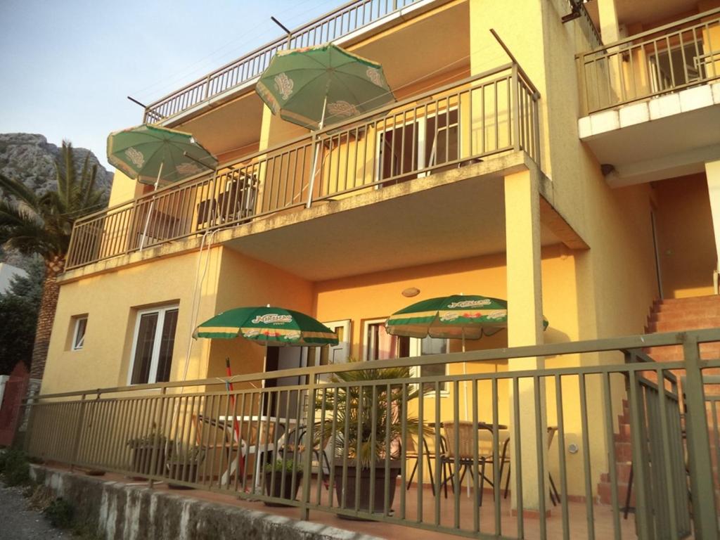 een balkon met tafels en stoelen met parasols bij Vito Apartments Sutomore in Sutomore