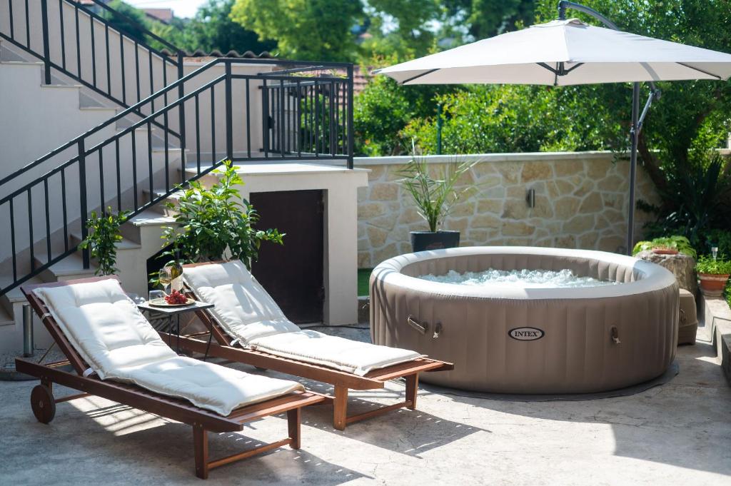 a hot tub with two lounge chairs and an umbrella at House Bany in Skradin