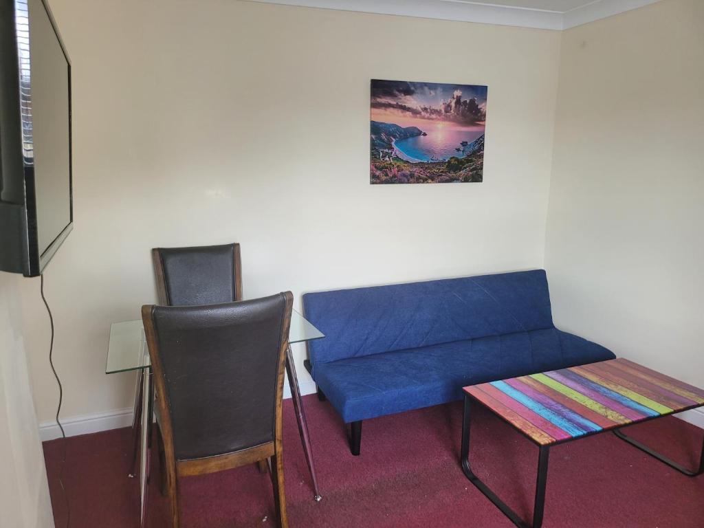 a room with a blue couch and a table and chairs at Comfy one bedroom flat in Tilehurst