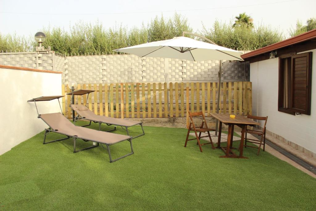a patio with a table and chairs and an umbrella at Il giardino di Mondello in Mondello