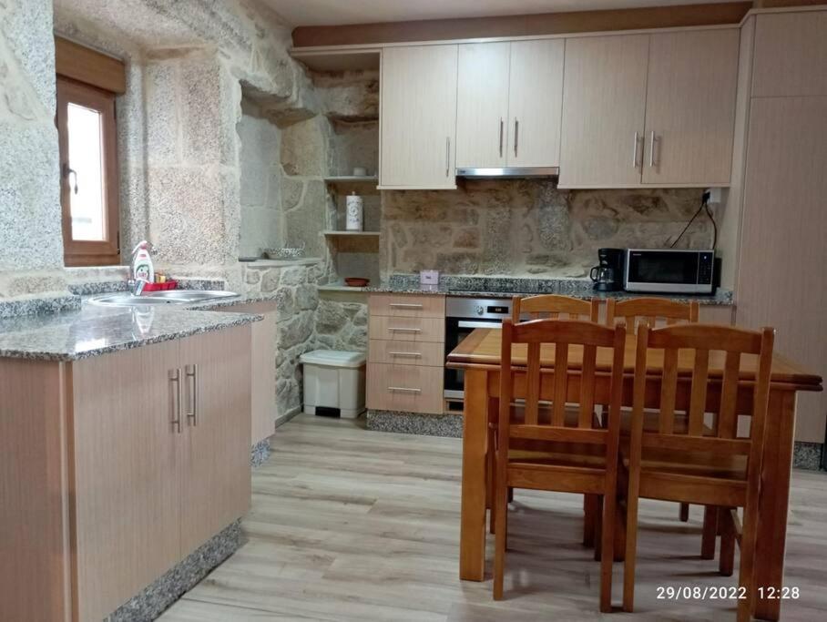 uma cozinha com cadeiras de madeira, uma mesa e um balcão em Casa de piedra céntrica. em Ribeira