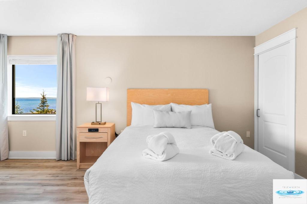 1 dormitorio con 1 cama con 2 toallas en Gold Coast Inn Breathtaking Sunsets Corner Lake View Room 208 en Traverse City