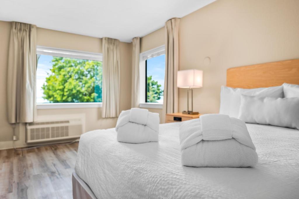 ein Hotelzimmer mit einem Bett und zwei Fenstern in der Unterkunft Gold Coast Inn Breathtaking Sunsets Corner Lake View Room 201 in Traverse City