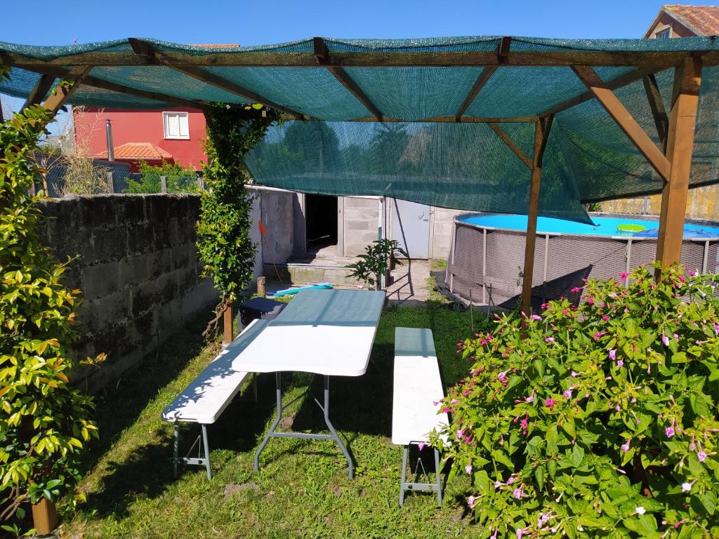 een picknicktafel en twee stoelen onder een luifel in een tuin bij A Balea Turquesa in Cangas de Morrazo