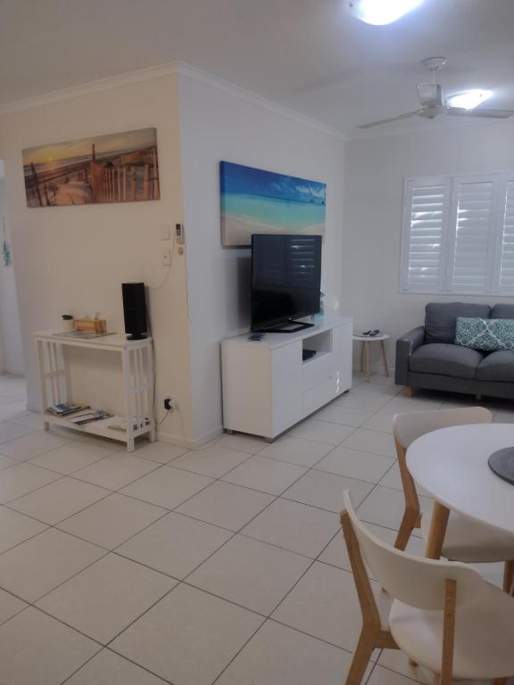 a living room with a couch and a tv at Ocean Breeze Apartments in Hervey Bay