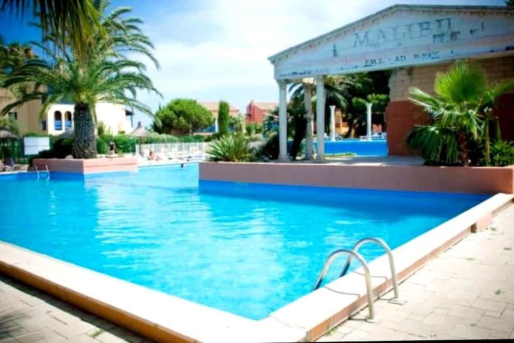 een groot zwembad met blauw water in een resort bij Petit paradis du 66,Canet Roussillon in Canet-en-Roussillon