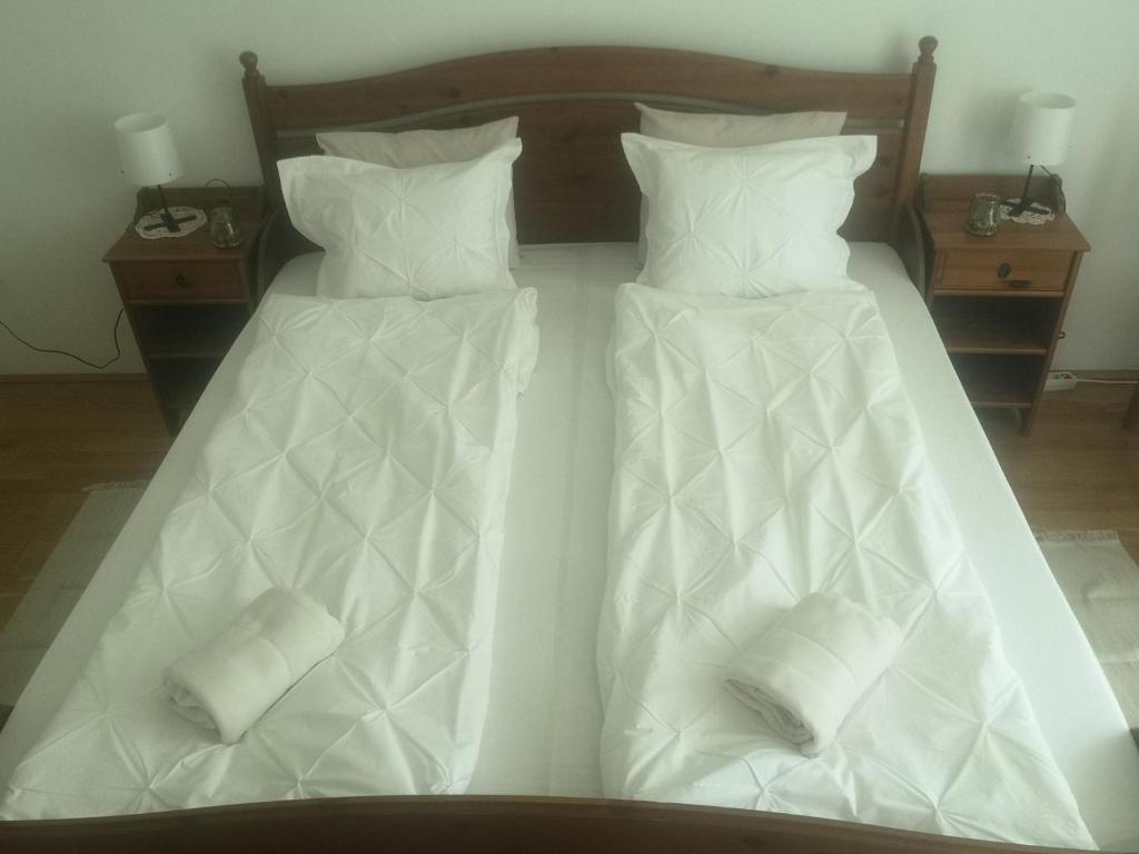 Duas camas com edredões brancos e almofadas em Antik Apartman em Veszprém