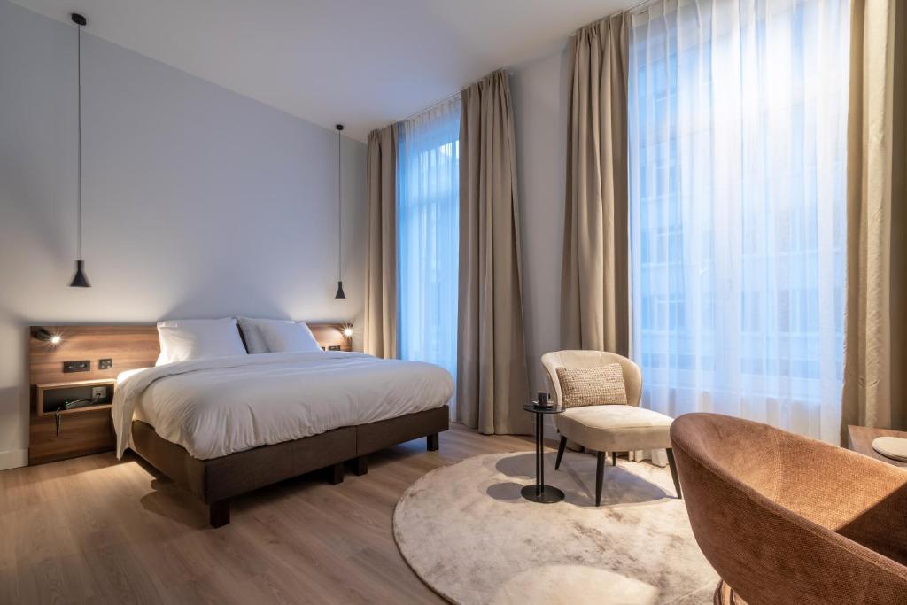 ein Schlafzimmer mit einem Bett, einem Sofa und einem Stuhl in der Unterkunft ONE TWO FOUR - Hotel & Spa in Gent