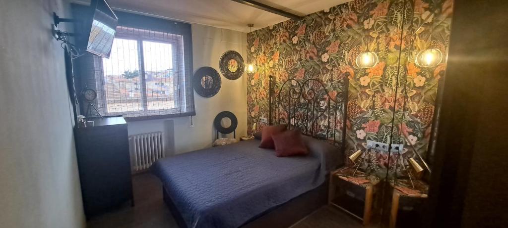 um pequeno quarto com uma cama e uma parede com papel de parede colorido em En el Cielo de Salamanca em Salamanca