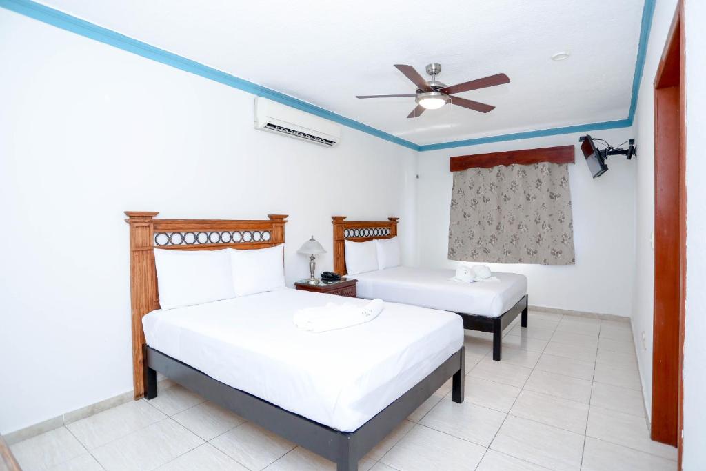 1 dormitorio con 2 camas y ventilador de techo en Hotel Avenida Cancun, en Cancún