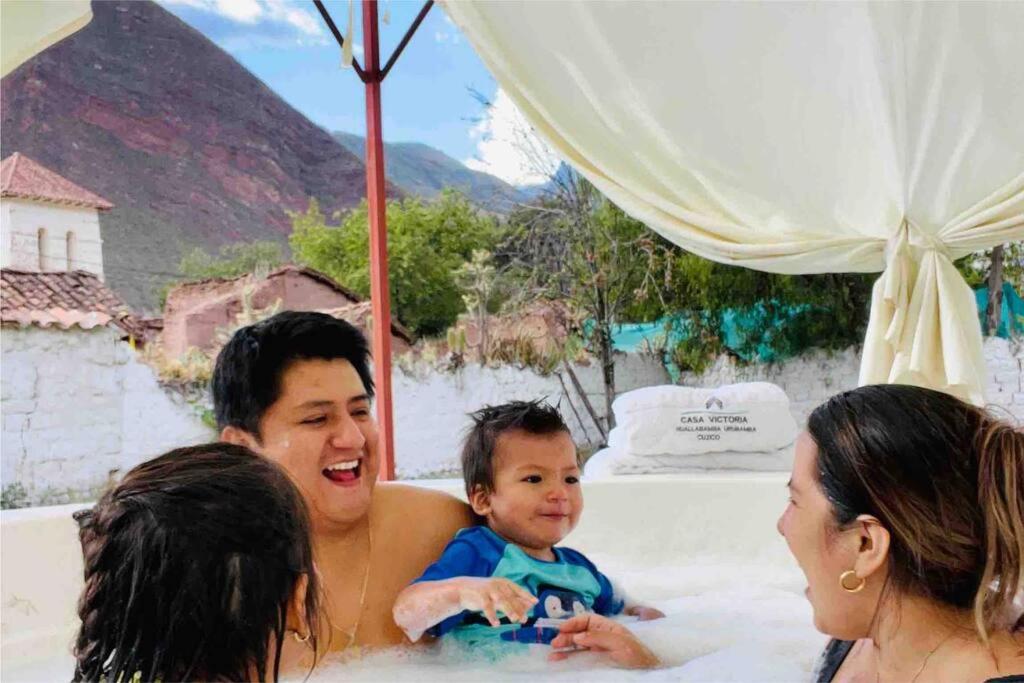 a man holding a baby in a bathtub with two women at Casa Machupicchu - Huayllabamba, Urubamba Cusco, Perú 
