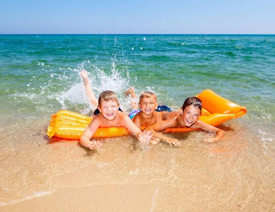 three children laying in the water on the beach at Didim Yazlik Ev 1 in Didim
