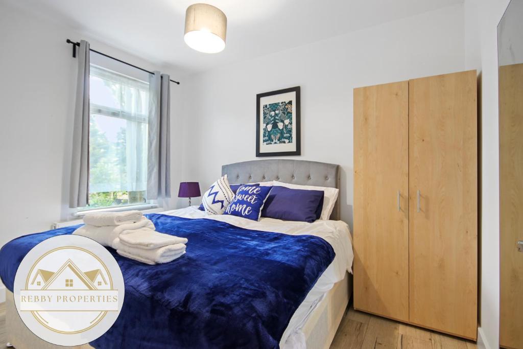 Schlafzimmer mit einem Bett mit blauer Decke in der Unterkunft 2 Bed home-Sleeps 5-near station & great location in London