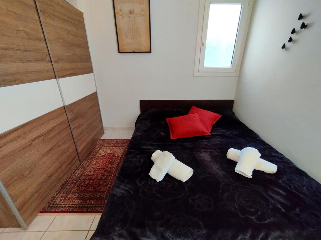 um quarto com uma cama com 2 almofadas e uma almofada vermelha em Antonia's cozy apartment em Agia Triada