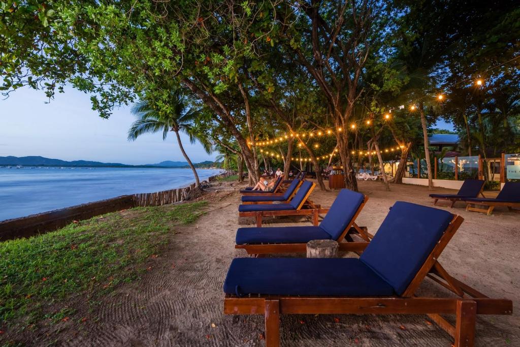 una fila di sedie a sdraio sulla spiaggia di notte di The Coast Beachfront Hotel a Tamarindo