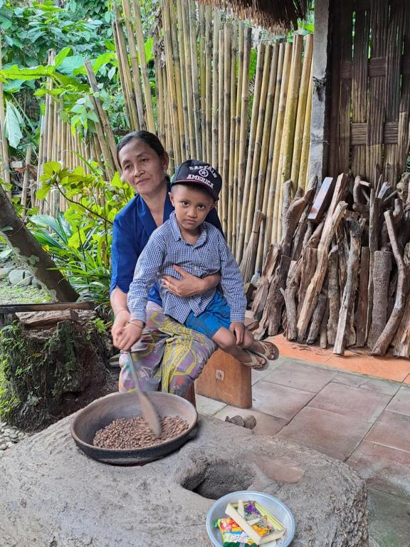 a man and a boy sitting next to a pot of food at Kubu Pilatus – Family House Lombok in Tjakranegara