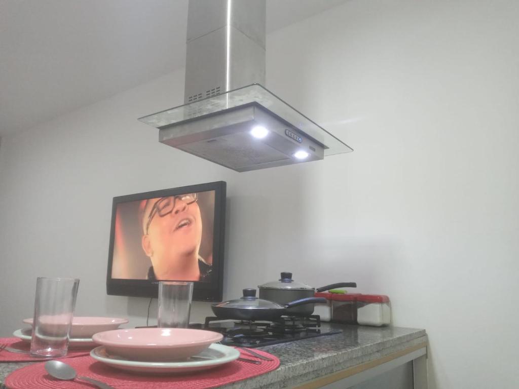 a kitchen with a stove and a tv on the wall at Deslumbrante Apartamento Central in Curitiba