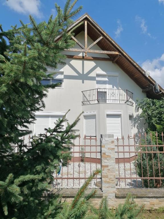 a white house with a fence and a tree at Anna Vendégház in Balatonőszöd