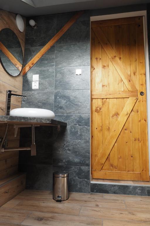 een badkamer met een houten deur en een wastafel bij Apartmán U Borovice in Bílá Třemešná