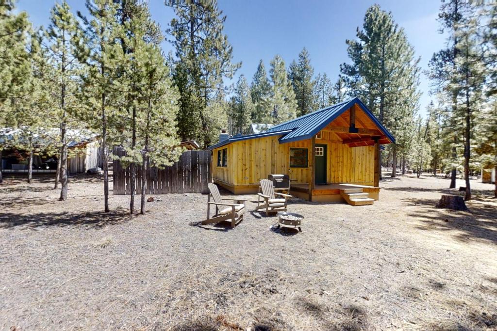 Crescent的住宿－Little Pine Cabin at Big Pine Retreat，一个小黄色小屋,配有长凳和椅子