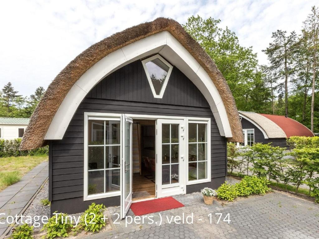 a small black cottage with a large arched window at Beautiful cottage with dishwasher, in a holiday park not far from Giethoorn in De Bult