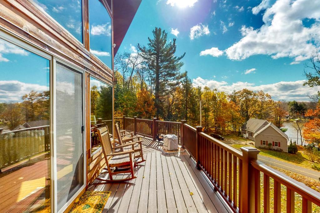 a deck with chairs and a view of the woods at Autumn Hill Lakehouse in Hinsdale