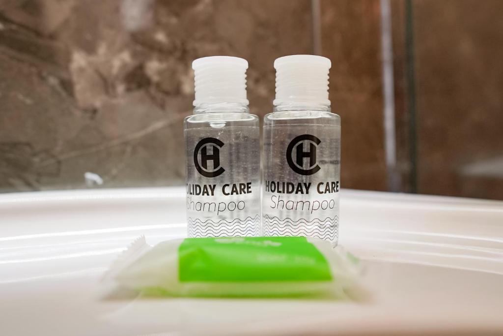 duas garrafas de pasta de dentes e uma esponja verde num lavatório em Mega Hotel em Gjirokastër