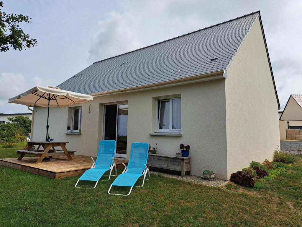 two blue chairs and an umbrella in front of a house at Single storey holiday home in Plouarzel in Plouarzel