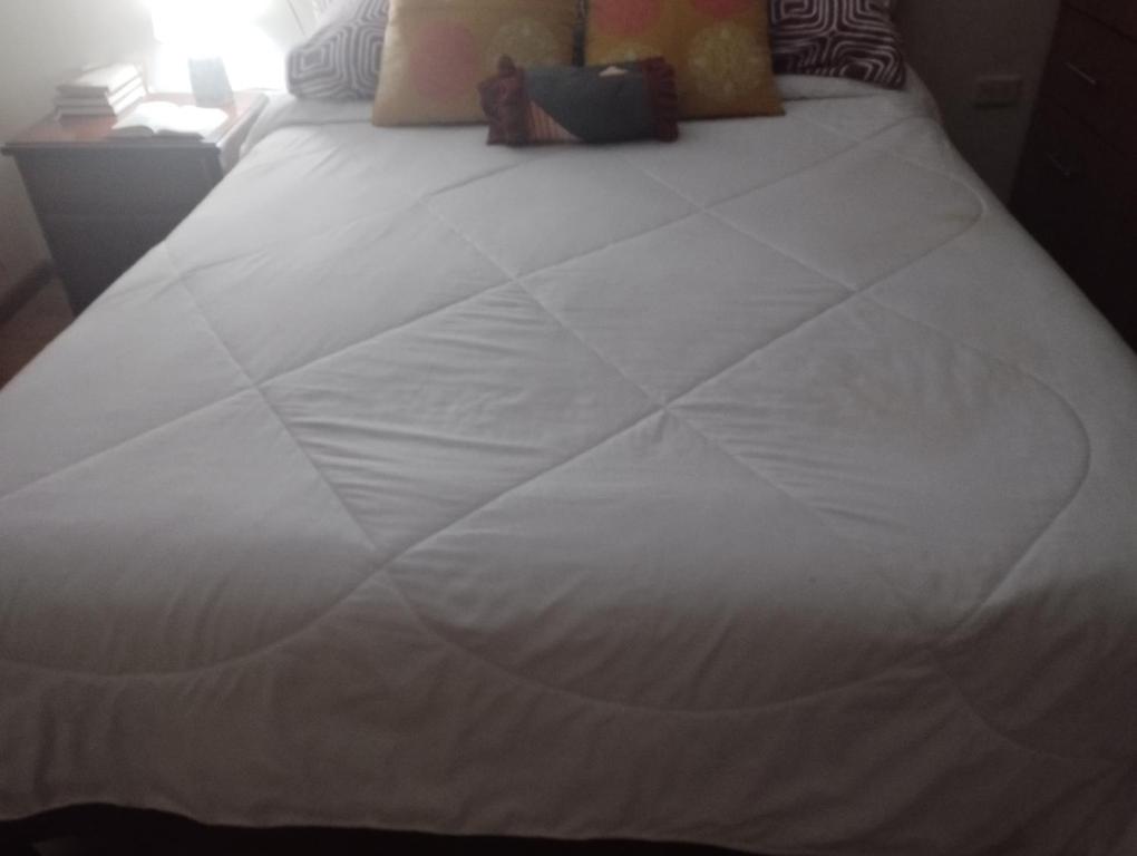 uma grande cama branca num quarto em Comfort city em Cuenca