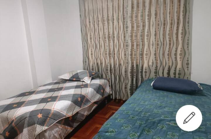 a bedroom with two beds and a window with curtains at Departamento céntrico in Huaraz
