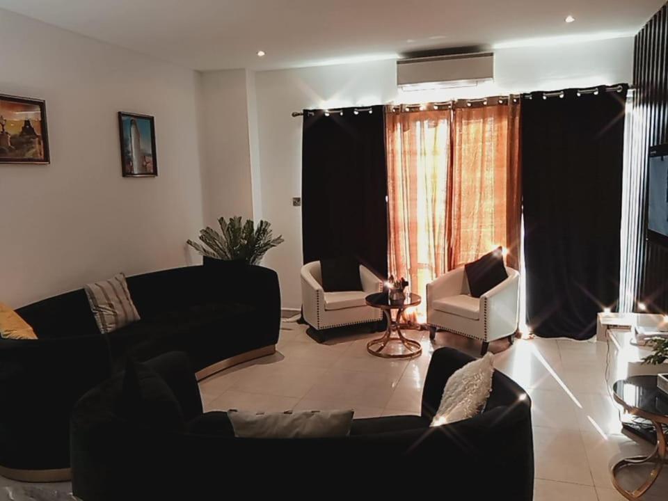 ein Wohnzimmer mit Sofas und Stühlen sowie einem Fenster in der Unterkunft KMAX PROPERTY in Accra